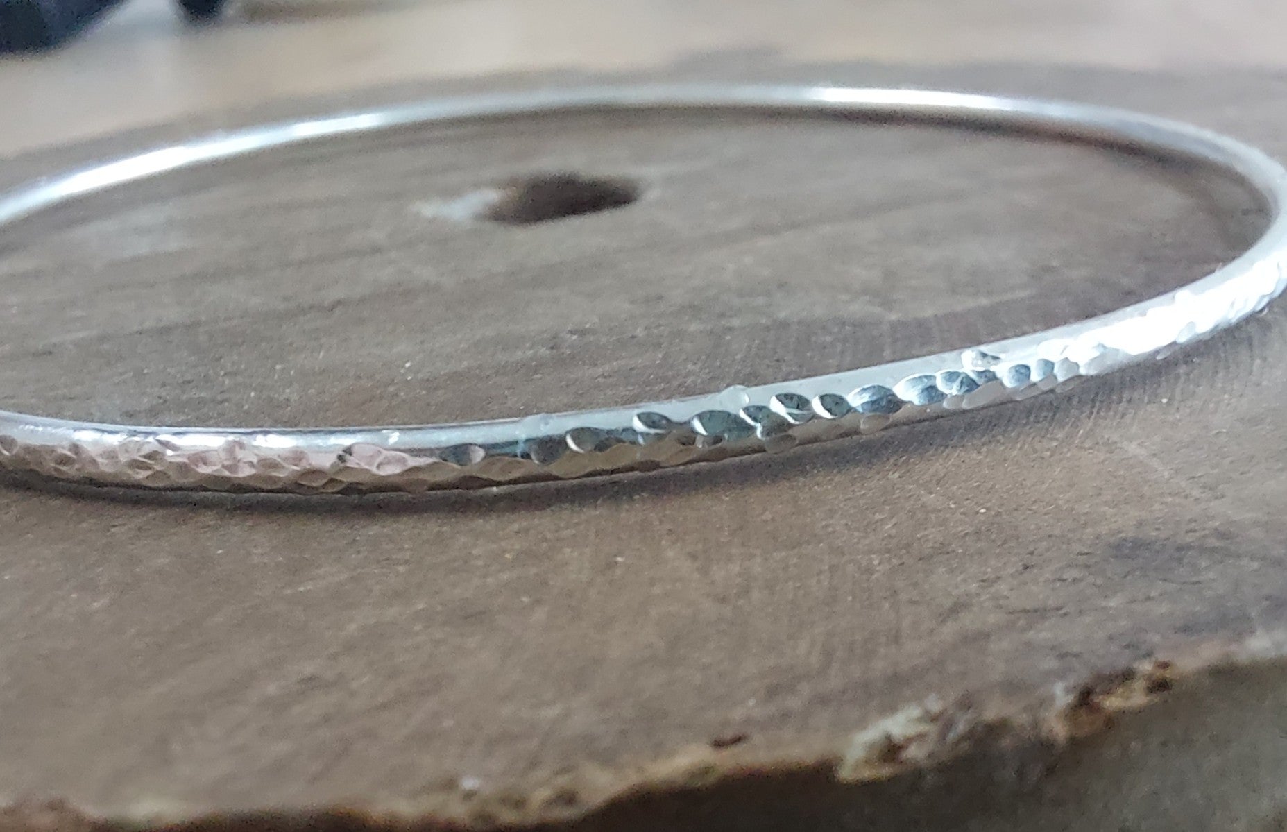 Silver bangle with a textured surface on a wooden background