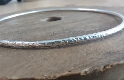 Silver bangle with a textured surface on a wooden background